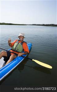 African American middle-aged man smiling and giving thumbs up gesure in kayak.