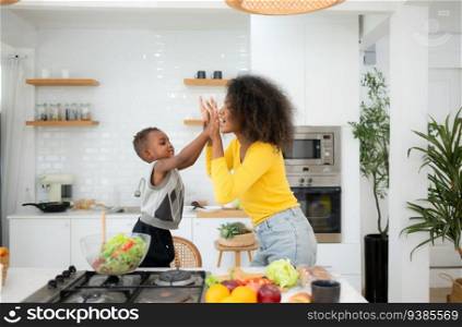 African American mother and son preparing salad together in the kitchen at home