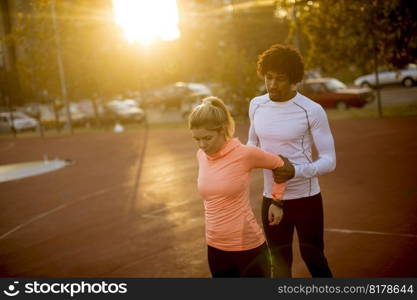African American personal trainer helping woman working exercise for arms at outdoor