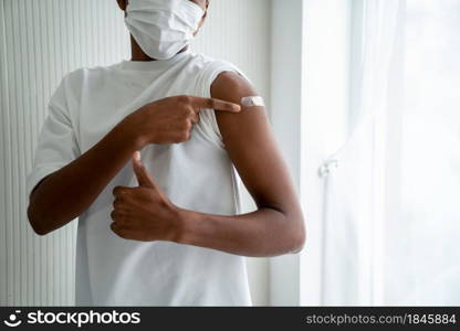 African American teenager showing COVID-19 vaccine bandage merrily in concept of coronavirus vaccination program to vaccinate citizen .. African American teenager showing COVID-19 vaccine bandage merrily