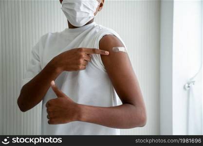 African American teenager showing COVID-19 vaccine bandage merrily in concept of coronavirus vaccination program to vaccinate citizen .. African American teenager showing COVID-19 vaccine bandage merrily