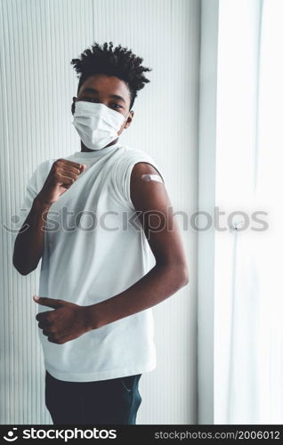 African American teenager showing COVID-19 vaccine bandage merrily in concept of coronavirus vaccination program to vaccinate citizen .. African American teenager showing COVID-19 vaccine bandage merrily