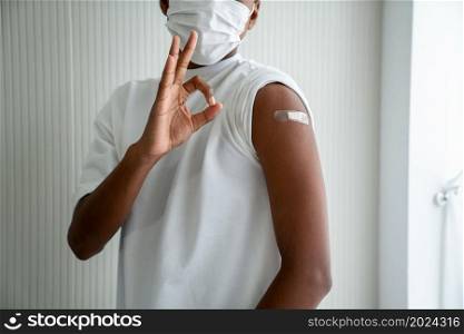 African American teenager showing COVID-19 vaccine bandage merrily in concept of coronavirus vaccination program to vaccinate citizen .. African American teenager showing COVID-19 vaccine bandage merrily