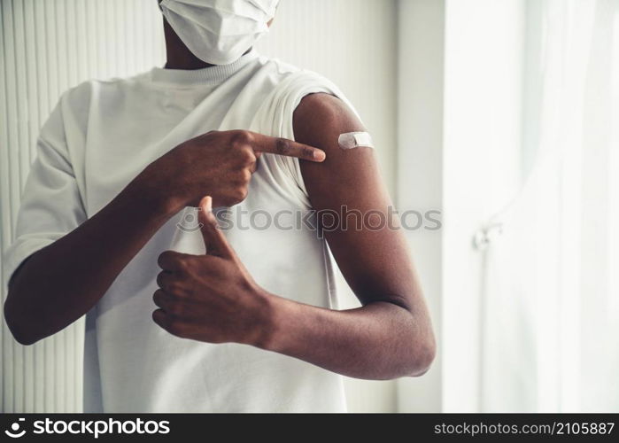 African American teenager showing COVID-19 vaccine bandage merrily in concept of coronavirus vaccination program to vaccinate citizen .. African American teenager showing COVID-19 vaccine bandage merrily