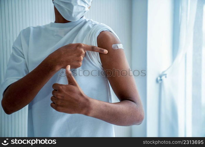 African American teenager showing COVID-19 vaccine bandage merrily in concept of coronavirus vaccination program to vaccinate citizen .. African American teenager showing COVID-19 vaccine bandage merrily