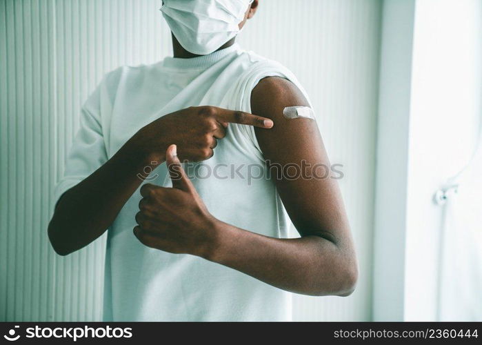 African American teenager showing COVID-19 vaccine bandage merrily in concept of coronavirus vaccination program to vaccinate citizen .. African American teenager showing COVID-19 vaccine bandage merrily