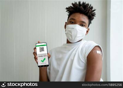 African American teenager shows vaccine passport on mobile phone to validate travel permission by the digital document. Vaccine Passport V5