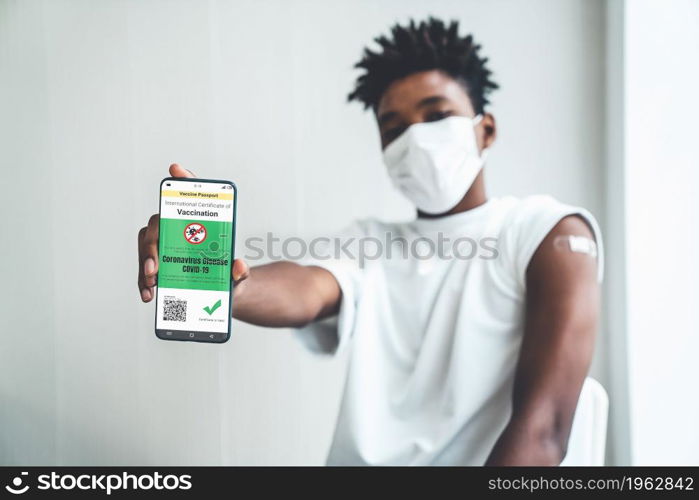 African American teenager shows vaccine passport on mobile phone to validate travel permission by the digital document. Vaccine Passport V5