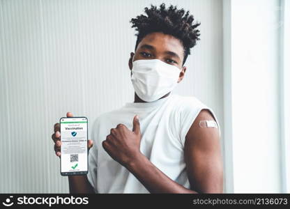 African American teenager shows vaccine passport on mobile phone to validate travel permission by the digital document. African American teenager shows vaccine passport on mobile phone