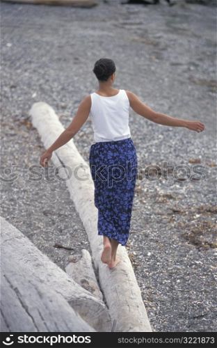 African American Walking Down A Log On A Rocky Beach