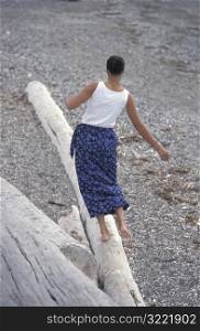 African American Walking Down A Log On A Rocky Beach