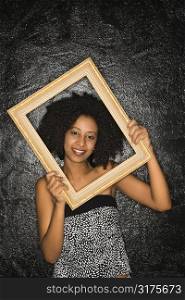 African-American woman holding frame over her face.