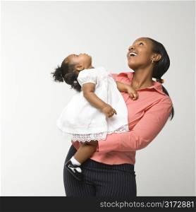 African American woman holding infant girl standing against white background.