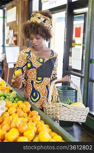 African American woman in traditional wear shopping for fruits at supermarket