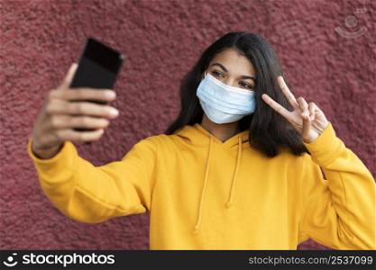 african american woman wearing medical mask taking selfie