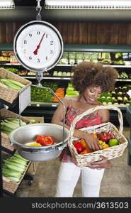 African American woman weighing bell peppers on scale at supermarket