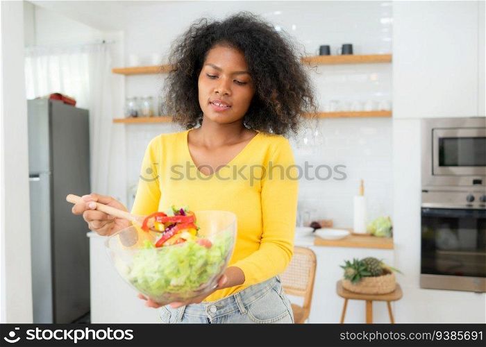 African American woman with bowl of salad in kitchen at home