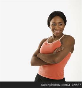 African American young adult woman in athletic wear smiling at viewer with arms crossed.