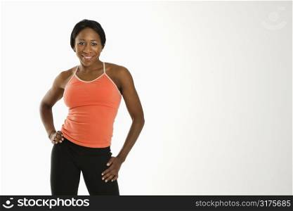African American young adult woman in athletic wear smiling at viewer with hands on hips.