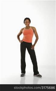African American young adult woman in athletic wear smiling at viewer with hands on hips.