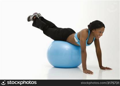 African American young adult woman working out with exercise ball.