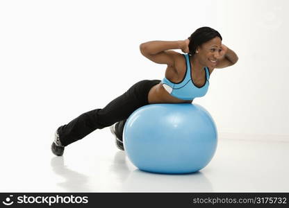 African American young adult woman working out with exercise ball.