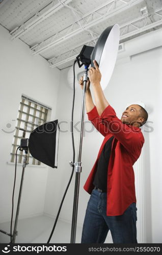 African American young male adult adjusting studio lights.