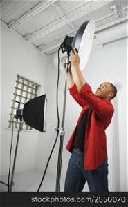 African American young male adult adjusting studio lights.