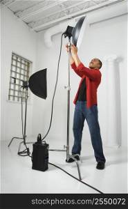 African American young male adult adjusting studio lights.