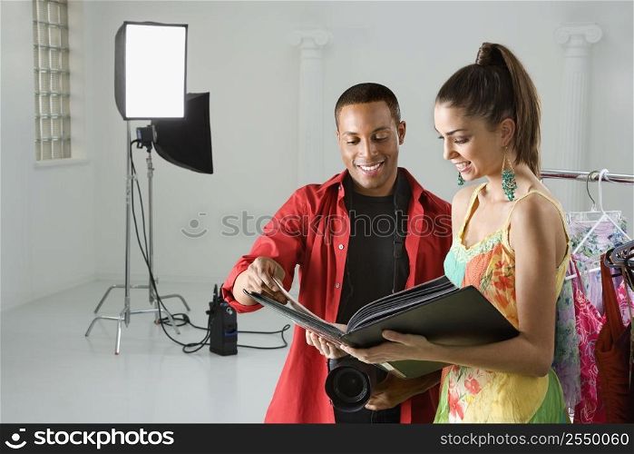 African American young male adult photographer and young adult female model looking at portfolio.