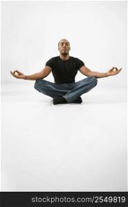 African American young male adult sitting meditating.