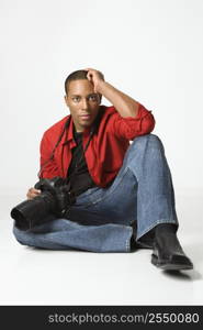 African American young male adult sitting on floor with camera.