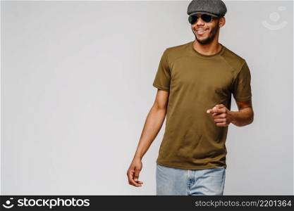 african-american young man in green t-shirt wearing sunglasses and cap over light grey background with copy space.. african-american young man in green t-shirt wearing sunglasses and cap over light grey background with copy space