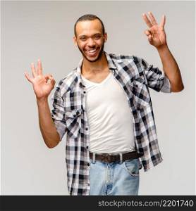 african-american young man wearing casual shirt and showing ok sign over light grey background.. african-american young man wearing casual shirt and showing ok sign over light grey background