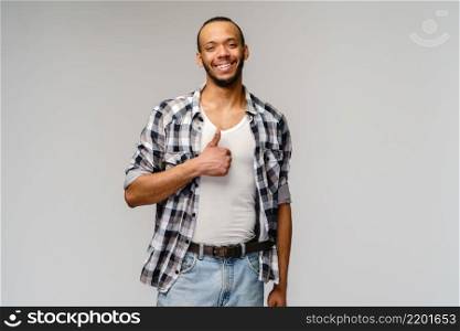 african-american young man wearing casual shirt and showing thumbs up over light grey background.. african-american young man wearing casual shirt and showing thumbs up over light grey background