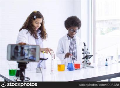 African black boy and caucasian teen girl streaming video clip of online studying science and experiment in classroom. Technology, Education and Diversity concept.
