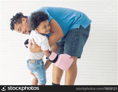 African black father is playing and boxing with his son in living room at home. Education and Family concept.