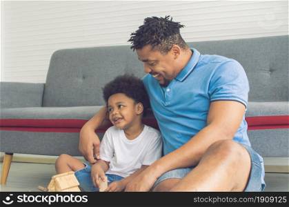 African black father is playing and hug his son in living room at home. Education and Family concept.