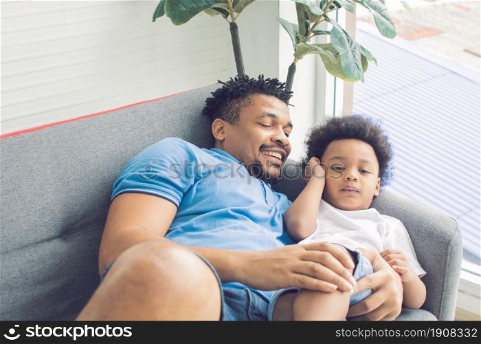 African black father is sleeping and playing with his son in living room at home. Education and Family concept.