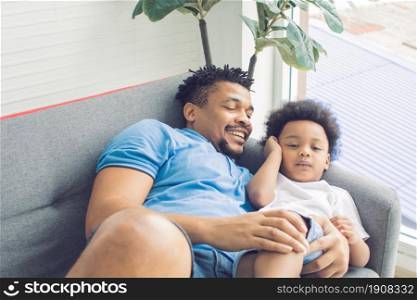 African black father is sleeping and playing with his son in living room at home. Education and Family concept.