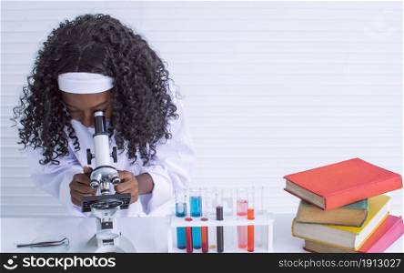African black girl studying science and using microscope in classroom at school. Education and diversity concept.