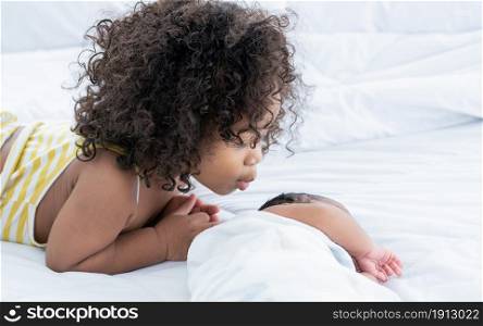 African black little girl kissing her brother with love and warmth while staying together at home. Family Concept.