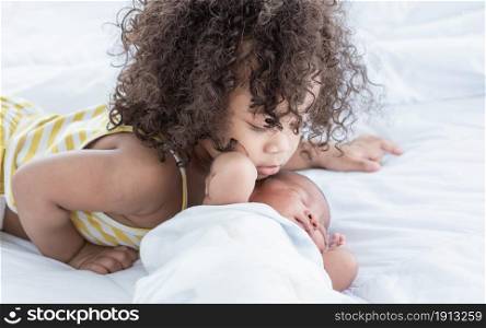 African black little girl kissing her brother with love and warmth while staying together at home. Family Concept.