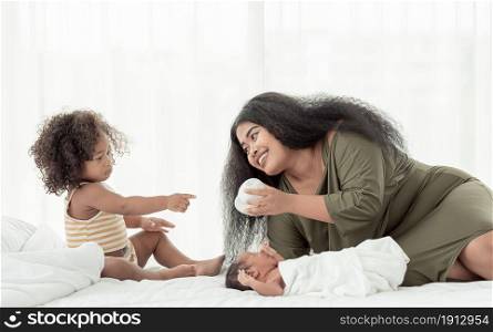 African black mom taking care of her baby son and little daughter in bedroom at home
