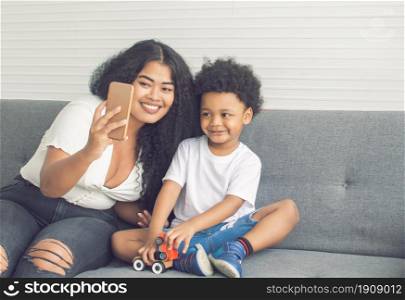 African black mother and little son taking selfie together in living room at home. Family, Diversity and Black Live Matters Concept.