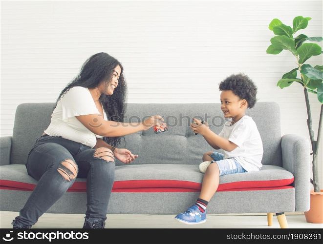 African black mother playing toys and spending time together with her son in living room at home