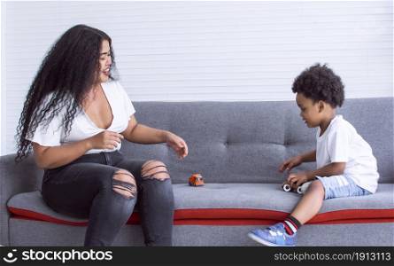 African black mother playing toys and spending time together with her son in living room at home