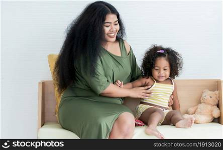 African black mother with afro hair playing with her little daughter in living room at home. Education and Family Concept.