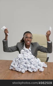 African business woman is tired of work . Sitting in front of crumpled paper pile . Unhappy with cv