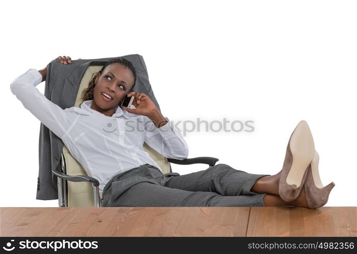 African business woman sitting at her desk and talking by phone isolated on white background